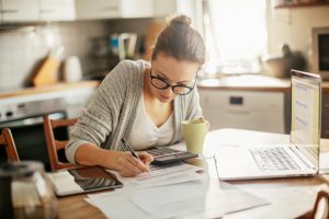 Close up of a young woman sitting in kitchen and going through her financials